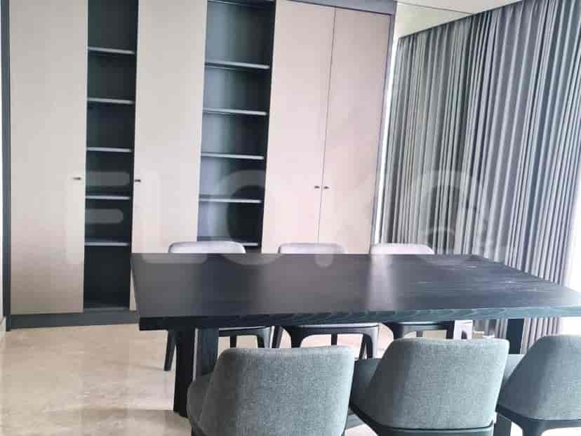 Area makan dengan meja hitam dan kursi dengan pemandangan ke ruang tamu dan dapur.