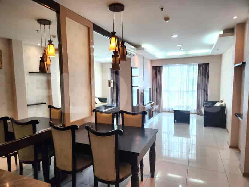 A dining area with a dark wooden dining table and chairs, decorated with hanging lights and a large mirror.