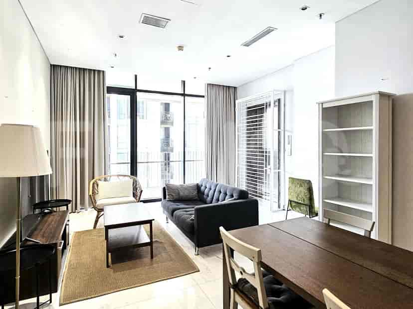 A living room with a grey sofa, rug, and large windows.