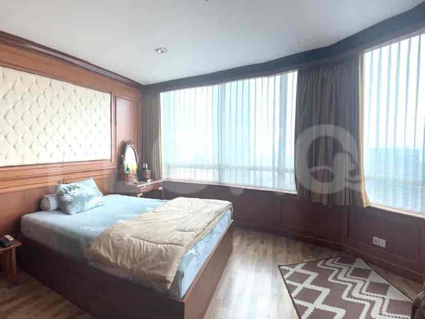 Bedroom with large windows, bed with headboard and side table.