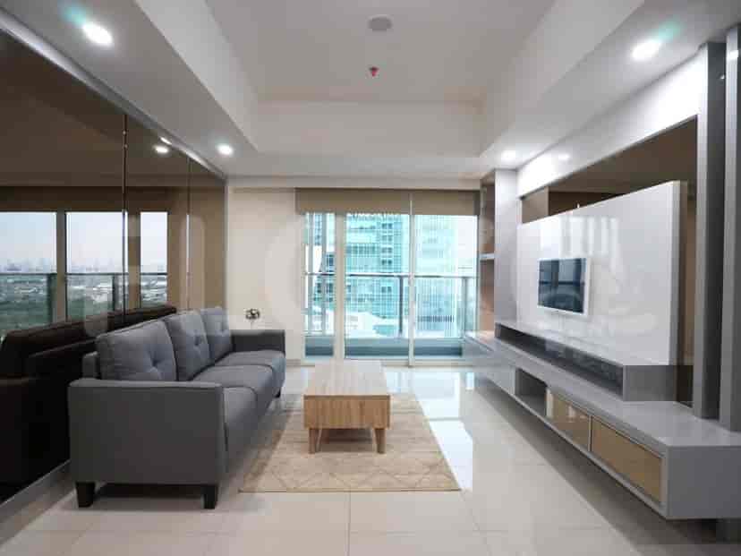 A well-lit living room with a modern design, featuring a grey sofa, coffee table, and large windows.
