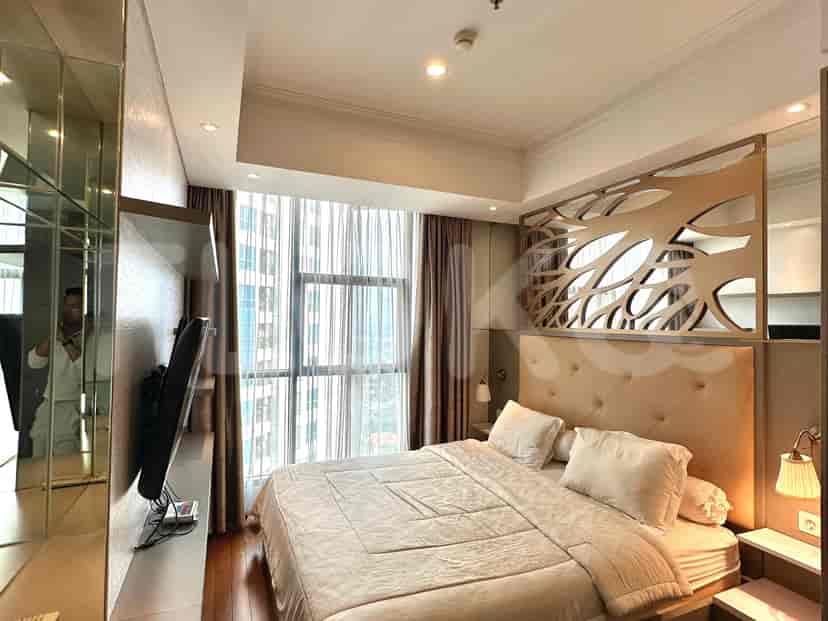 Bedroom featuring a bed, a wall-mounted TV, and large windows.