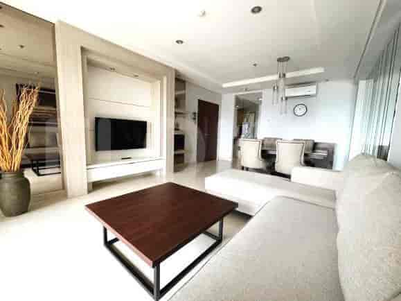 Living space featuring a dark wooden coffee table, a sectioned wall with a mounted TV, and a dining area.