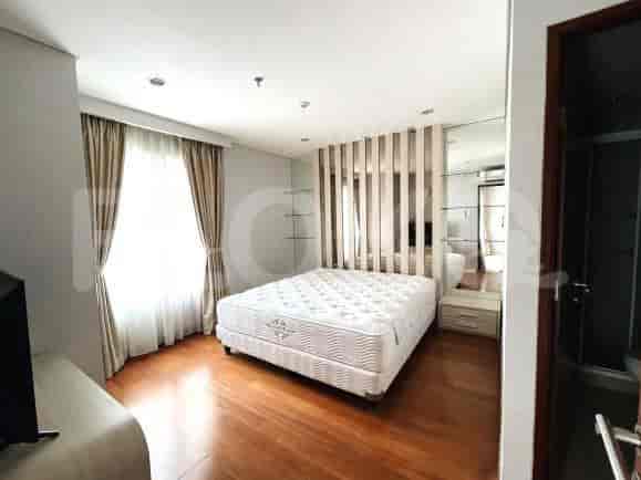 A bedroom featuring a large bed with a headboard composed of wooden panels and large mirrored wardrobe.