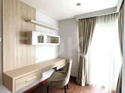 A study or office area with a built-in desk, floating shelves, and a window with sheer curtains.