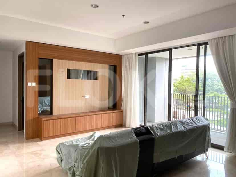 Sebuah ruang tamu modern dengan unit hiburan kayu, jendela besar berjendela, dan sofa yang ditutupi lapisan pelindung.