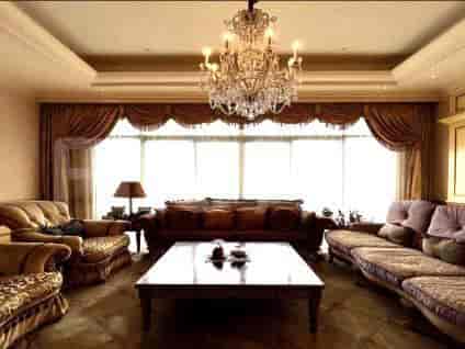 Elegant living room with a large chandelier, patterned curtains, and multiple seating areas.