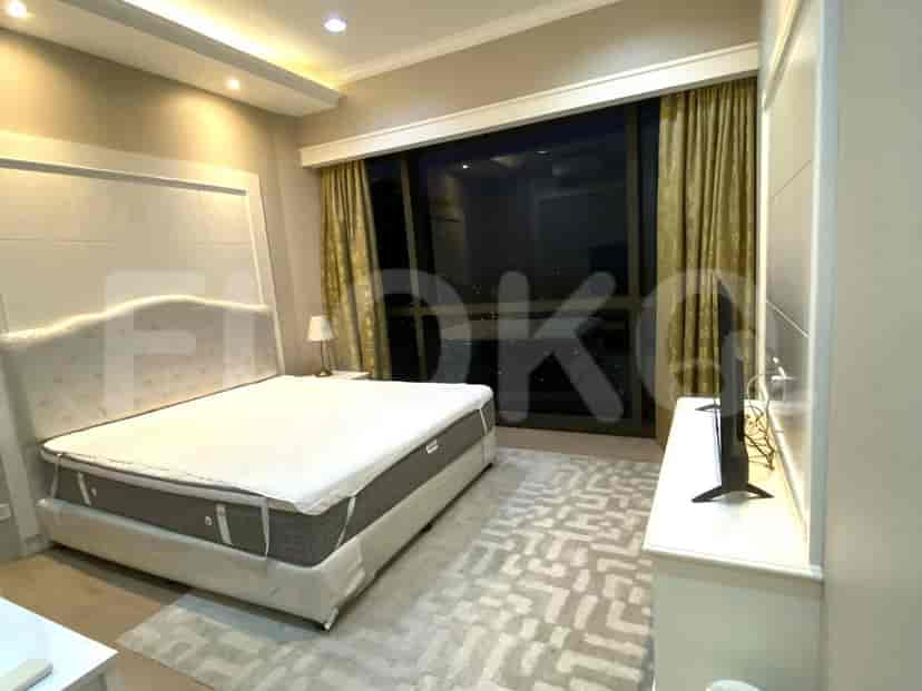 A bedroom with a large bed, a TV, and a window overlooking a city.