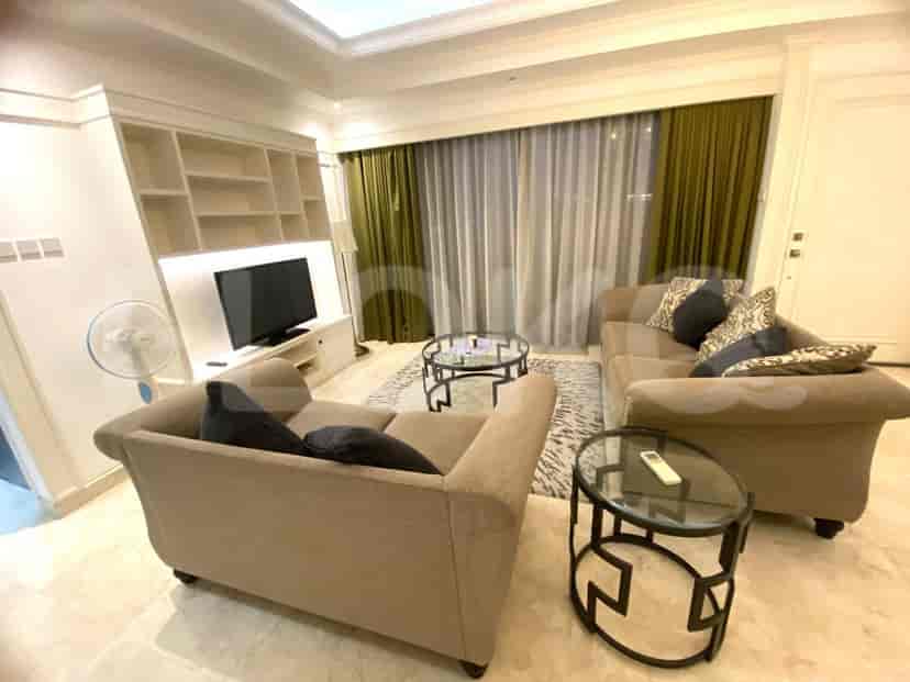 A modern living room with two beige sofas, a TV, and glass-top tables.