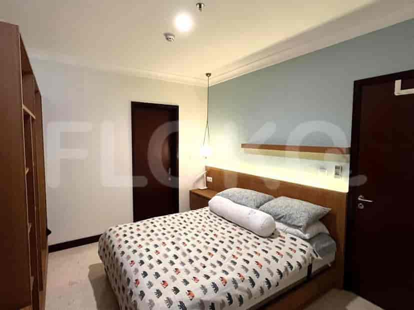 A bedroom with a bed, side table, and artwork.
