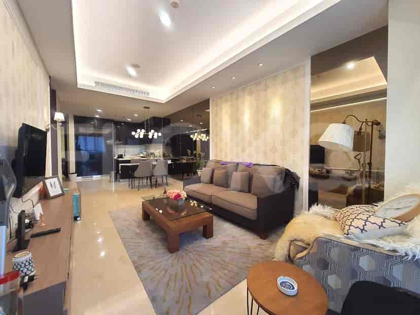 Spacious living room with a grey sofa, coffee table, dining area in the background, and a kitchen area.
