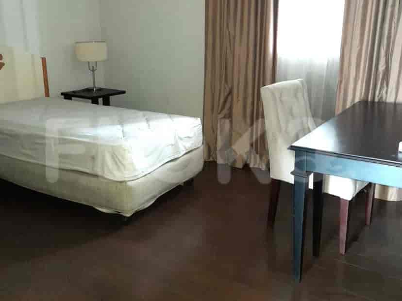 A simple bedroom with a bed, side table, and a small dining table.