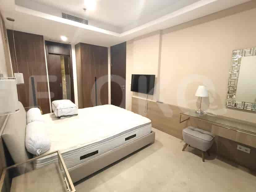 A modern bedroom with a large bed, a TV, and a vanity area.