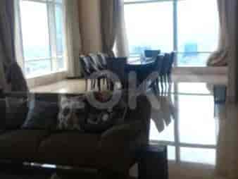 A spacious living and dining area featuring floor-to-ceiling windows, a dining table with chairs, and a large sofa.