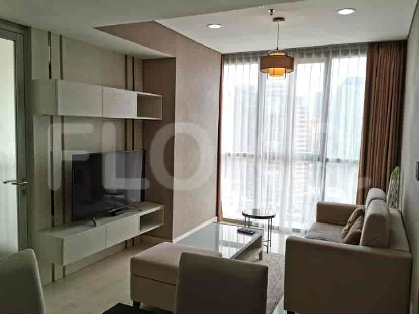 Modern living room with a grey sofa, a wall-mounted TV, and a dining area.