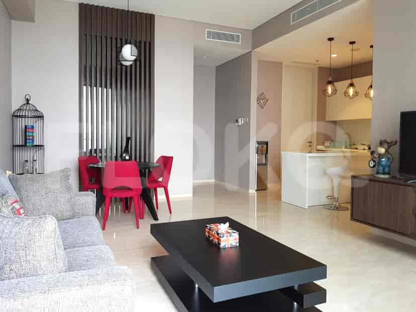 Modern living and dining area with grey sofa, red dining chairs, and open kitchen.