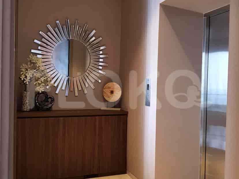 Hallway view with sunburst mirror, wooden cabinet, and elevator access.
