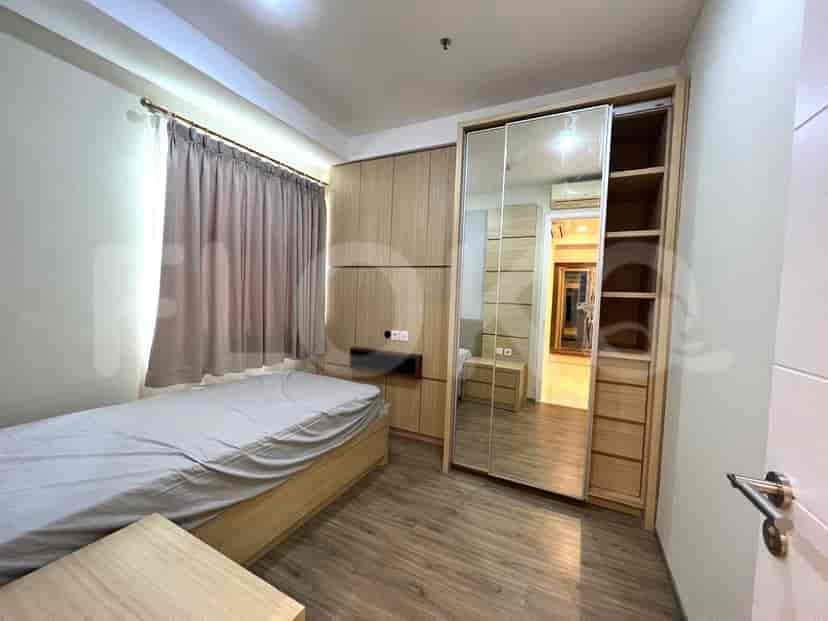 Kamar tidur modern dengan tempat tidur, lemari pakaian, dan meja samping kayu.