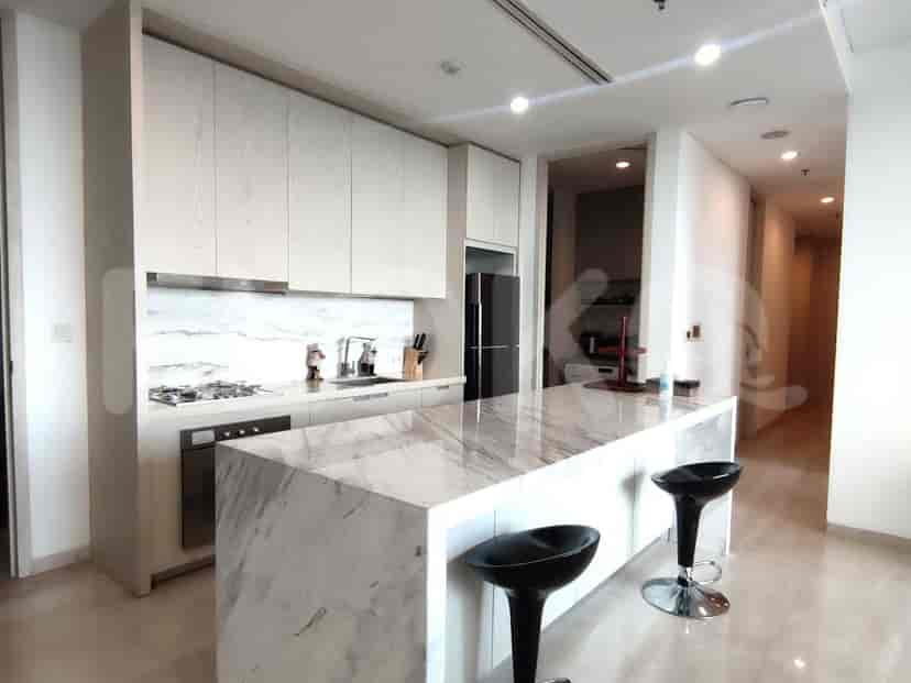 Dapur modern dengan pulau, bangku bar, dan lemari berwarna terang.