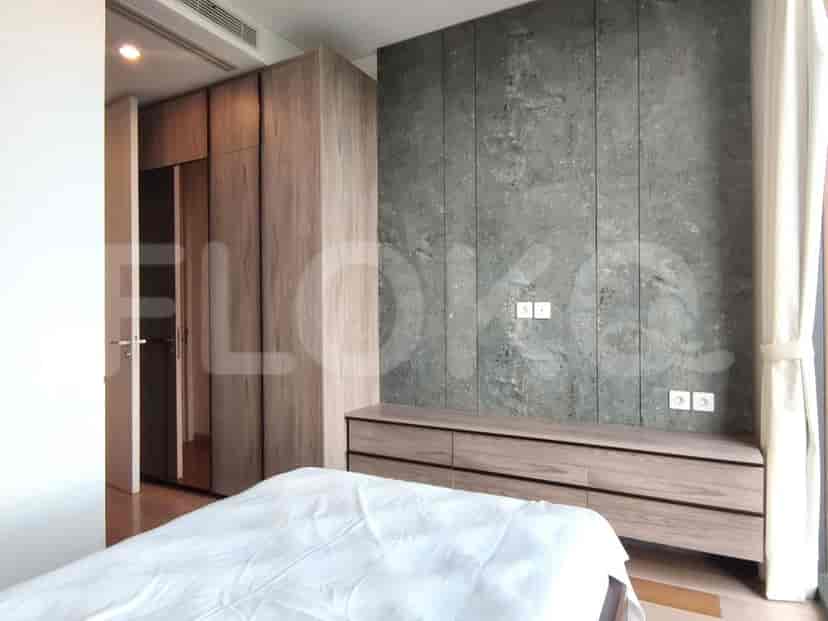 Kamar tidur yang menampilkan tempat tidur besar, lemari modern, dan dinding aksen bergaya beton.