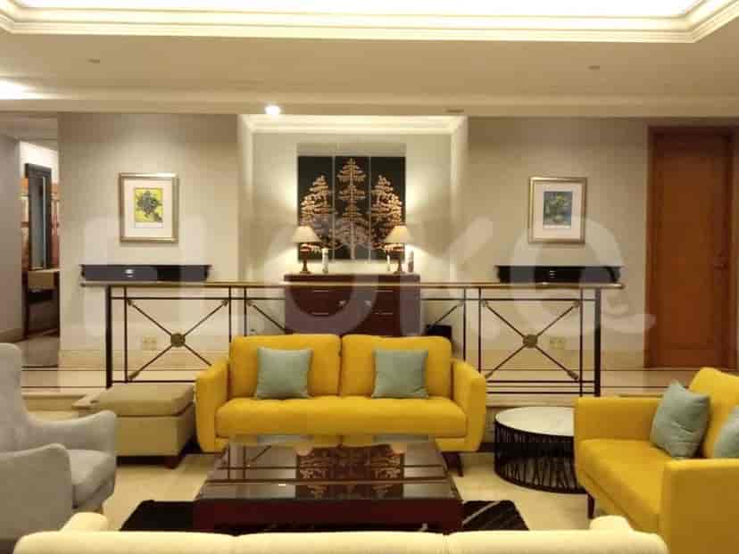 A well-lit lobby with yellow sofas, a decorative wooden cabinet, and framed artwork.