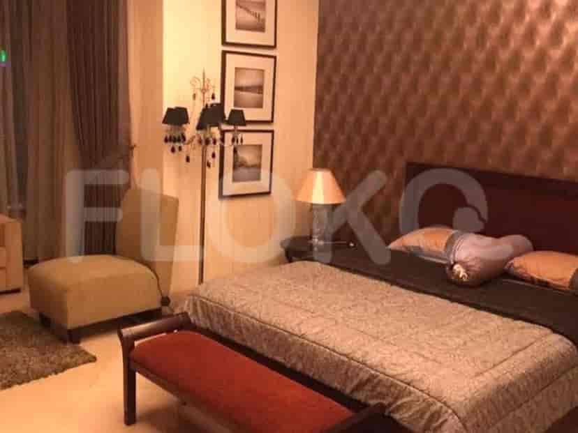 A bedroom featuring a bed with a patterned comforter, bedside lamps, and artwork.