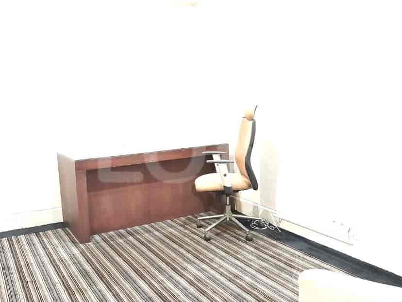 An office space with a wooden desk and an ergonomic chair.