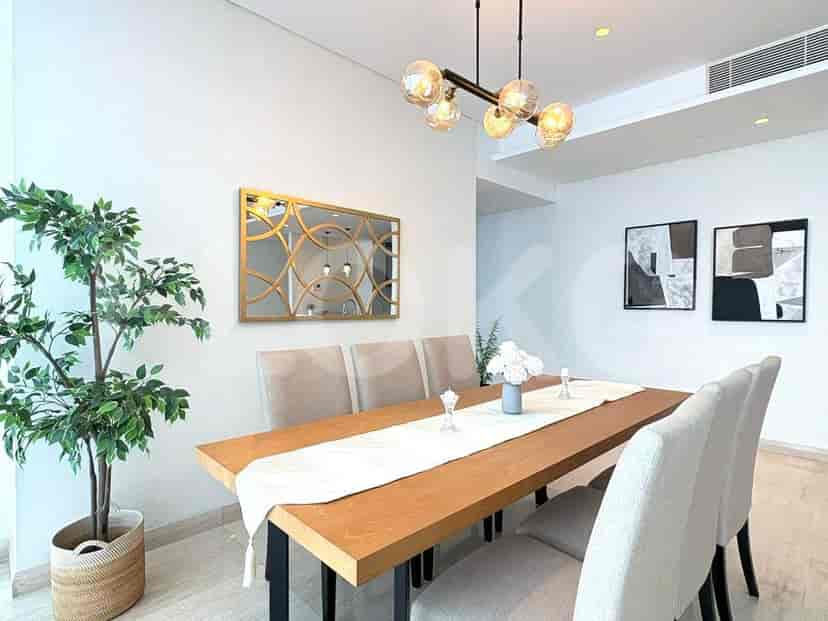 Dining area with a wooden table, stylish chairs, and decorative mirror.