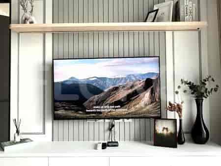 A living room with a wall-mounted TV, shelf, and decorations.