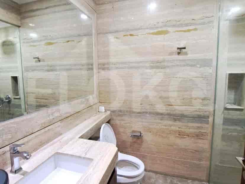 A well-appointed bathroom featuring marble walls, a modern sink, and a clean toilet.