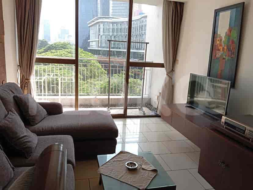 A spacious living room with an L-shaped grey sofa, wall-mounted smart TV, and large window.