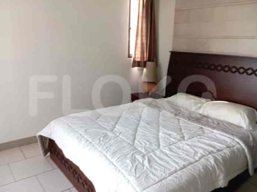 A cozy bedroom with a double bed, lamp on the bedside table and a window with curtains.