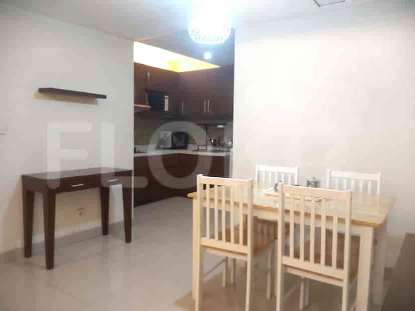 Dining area with a wooden table and chairs, adjacent to a kitchen with cabinets and appliances.