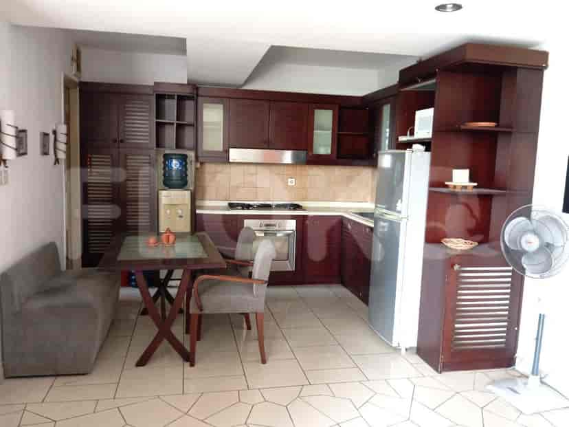 A modern kitchen with wooden cabinets, a refrigerator, and a dining table.