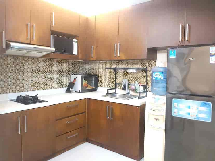The kitchen area boasts dark wooden cabinets and a range of modern appliances.