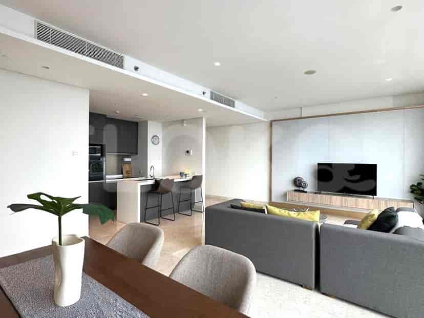 Living area showing the open kitchen, dining area, and a view of the living room with a TV and sofa.