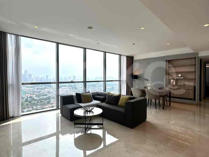 Spacious living area with floor-to-ceiling windows offering city views, a grey L-shaped sofa, and a round coffee table.
