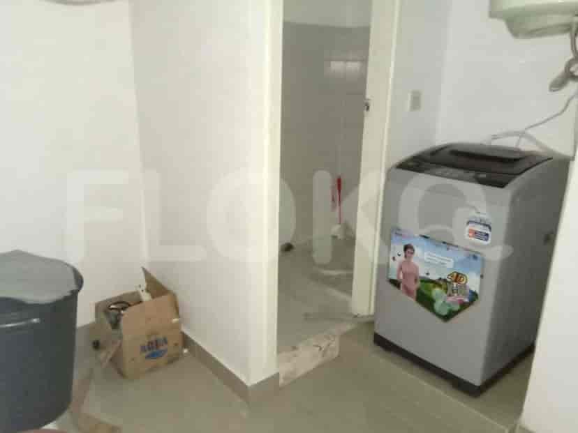 A small room with a washing machine and toilet.
