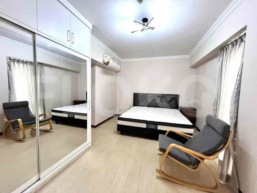 A large bedroom featuring a bed, closet, and chairs.