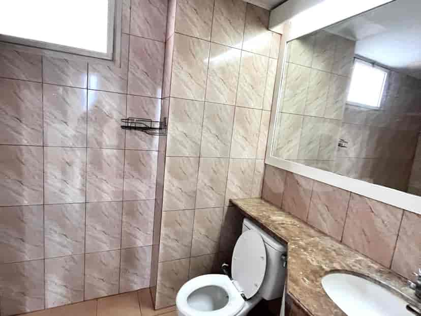 Bathroom with a toilet, sink, and tiled walls.