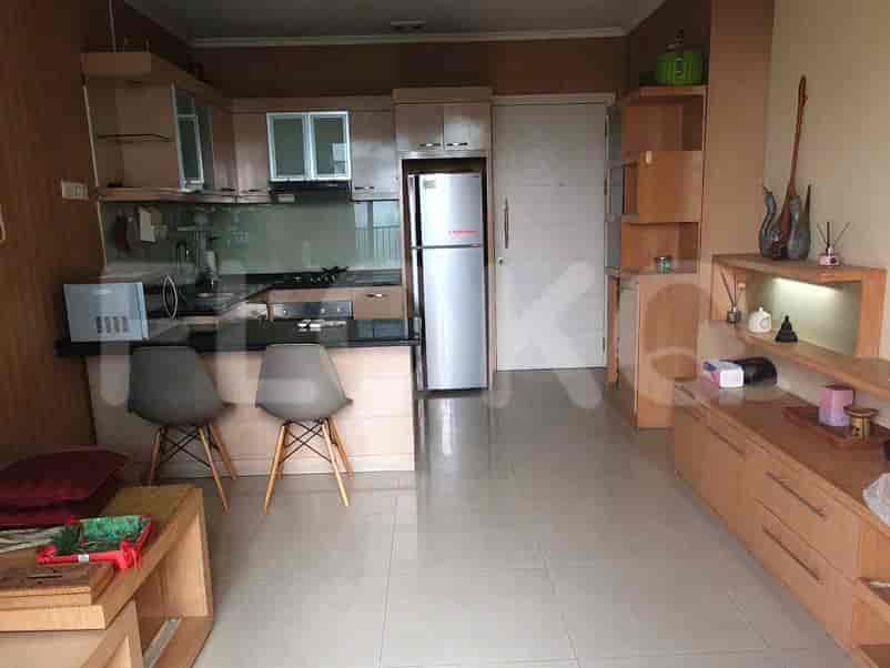 Open-plan living area with a kitchen featuring a refrigerator and a small dining table.
