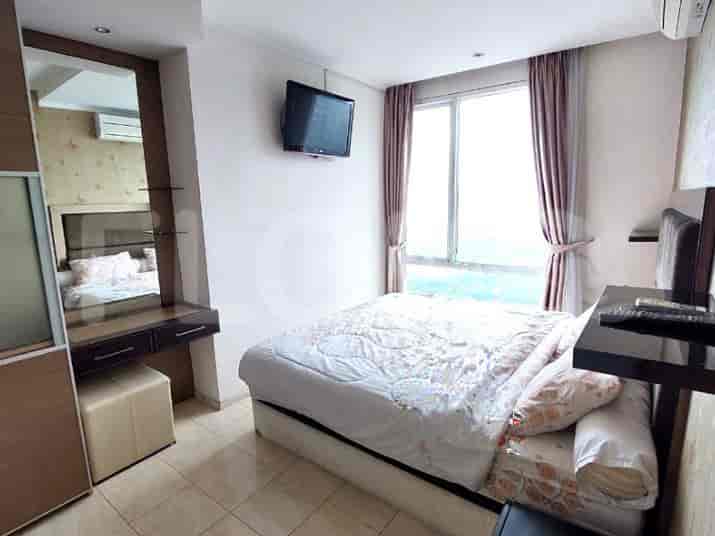 A bedroom featuring a bed, a vanity, and a large window with curtains.