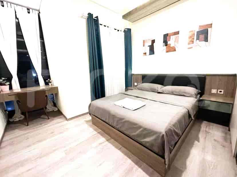 Modern bedroom with a grey bed, artwork, and wooden elements.