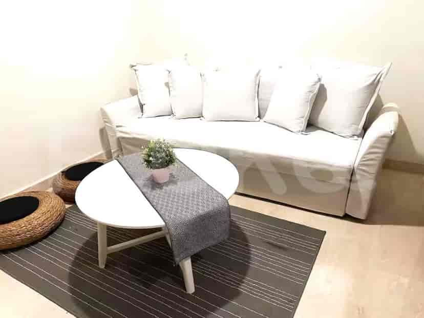 A bright living room featuring a white sofa, small round table, and decorative elements.