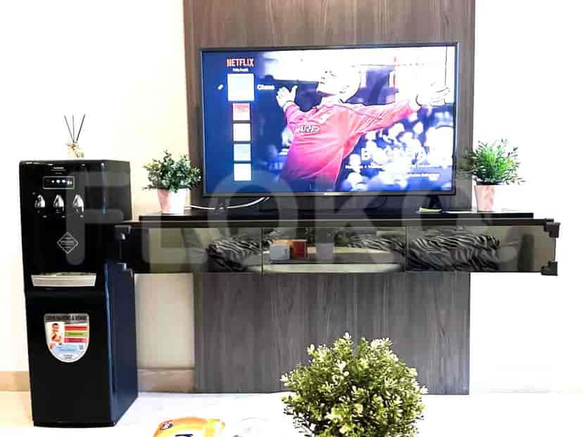 Living room with a wall-mounted TV, water dispenser, and decorative elements.