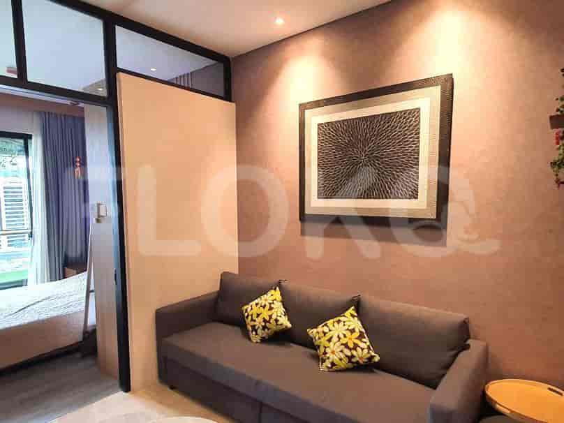 A living room with a grey sofa, artwork, and access to other rooms.