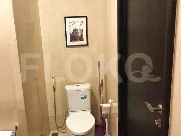 A modern bathroom with a toilet and framed artwork.