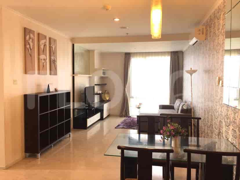 Area tamu yang luas dengan sofa, meja makan, TV yang dipasang di dinding, dan wallpaper bermotif.