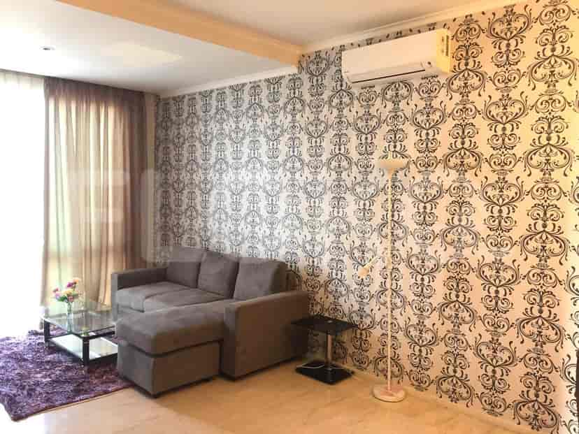 Tampilan dekat ruang tamu dengan sofa, wallpaper bermotif, dan lampu lantai.