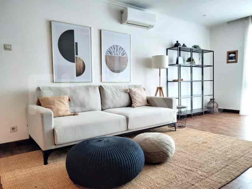 Ruang tamu yang luas dengan sofa berwarna krem, karya seni, dan karpet dekoratif.